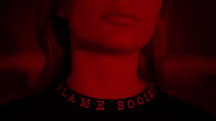 a woman wearing a black shirt with a red light behind her