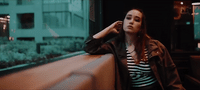 a woman leaning against a wall talking on a cell phone