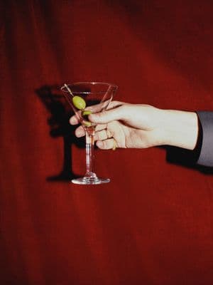 a person holding a martini glass with an olive in it