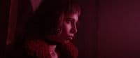 a woman in a dark room with a red light