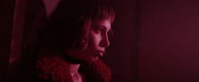 a woman in a dark room with a red light