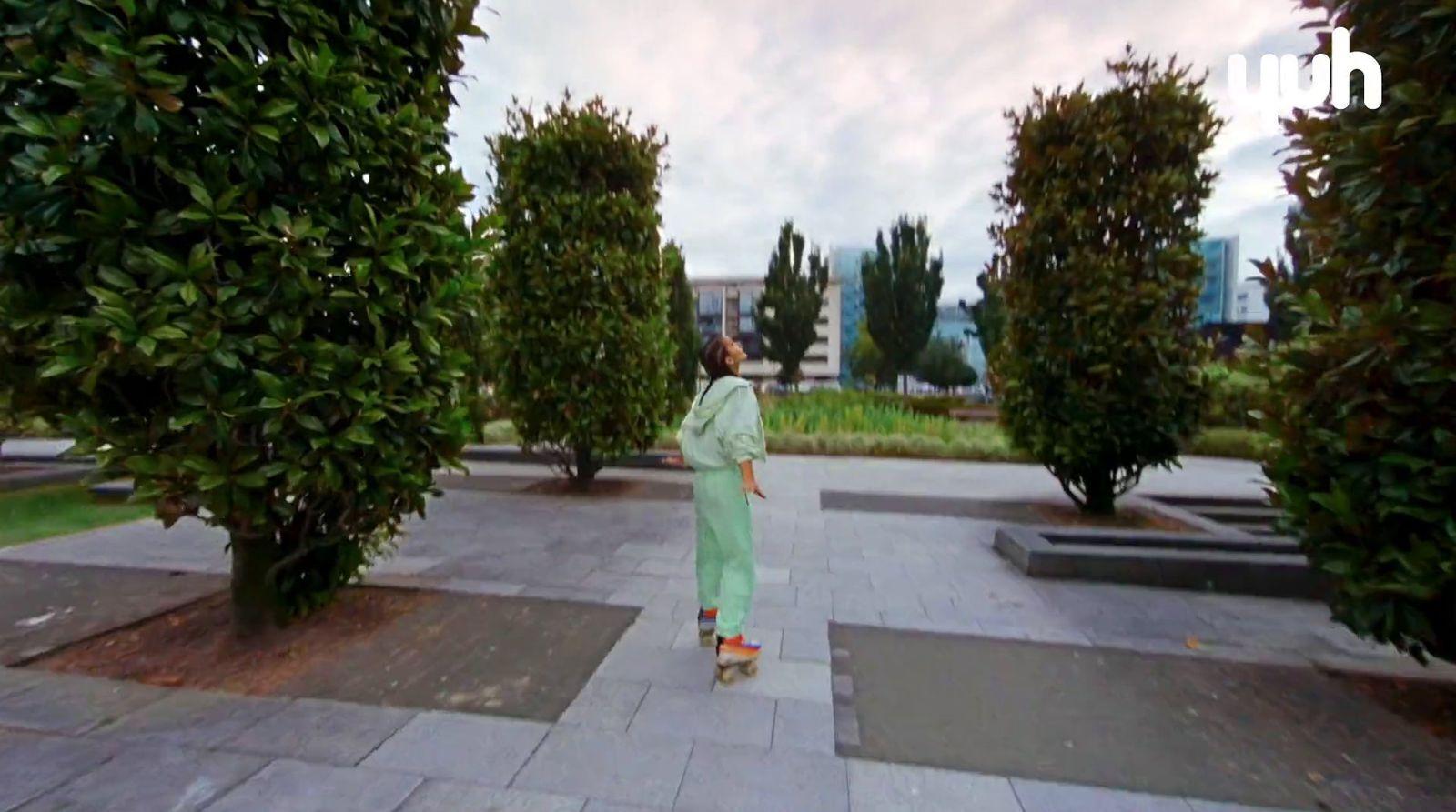 a woman in a long green dress walking through a park