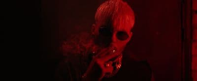 a woman with red hair and sunglasses smoking a cigarette