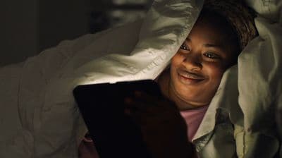 a woman is smiling while looking at a tablet