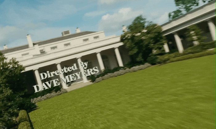 a large white building with trees and bushes in front of it