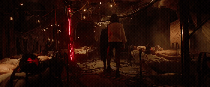 a man standing in a dark room next to a bed