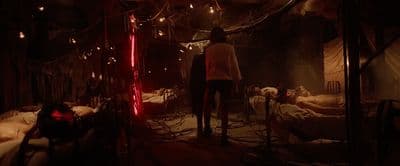 a man standing in a dark room next to a bed