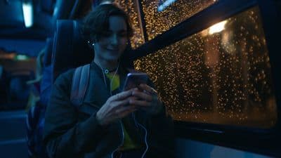 a person sitting on a bus looking at a cell phone