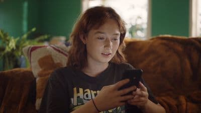 a woman sitting on a couch looking at a cell phone