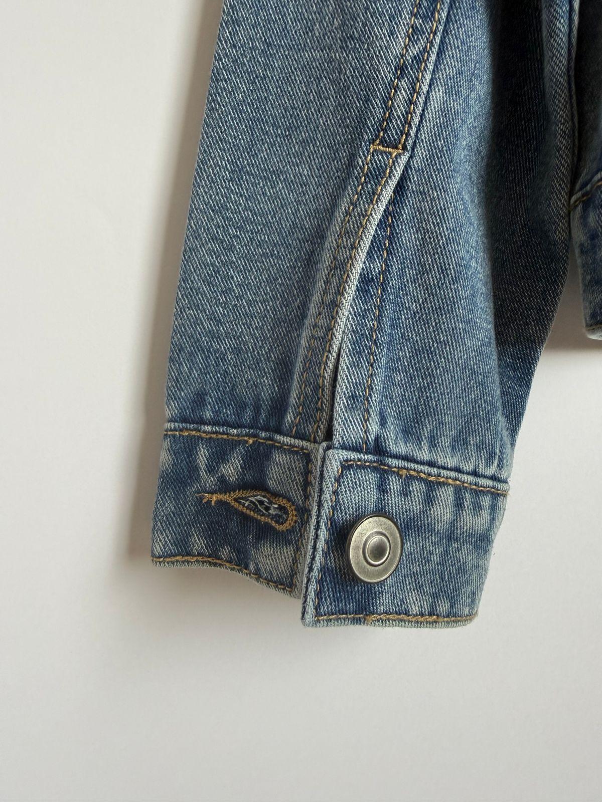 a blue jean jacket with a button on the back of it