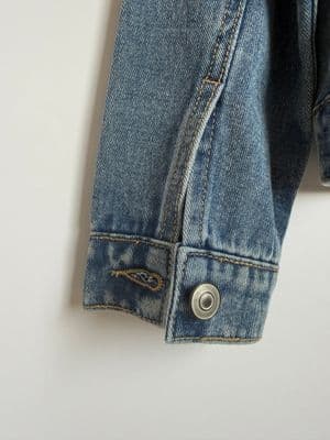 a blue jean jacket with a button on the back of it