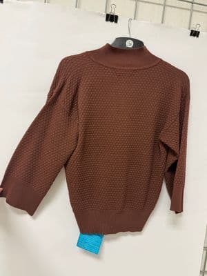 a brown sweater hanging on a white wall