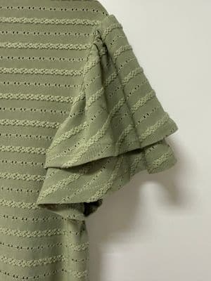 a green sweater hanging on a white wall