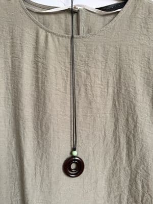 a white shirt with a brown necklace hanging from it