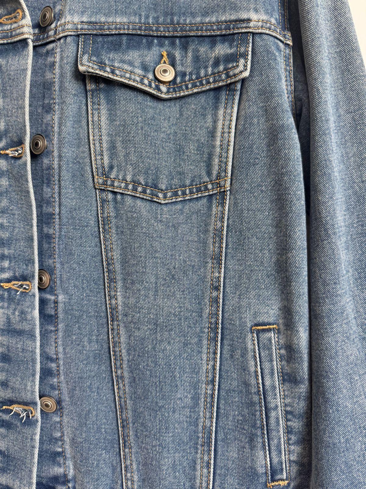 a blue jean jacket is hanging on a hanger