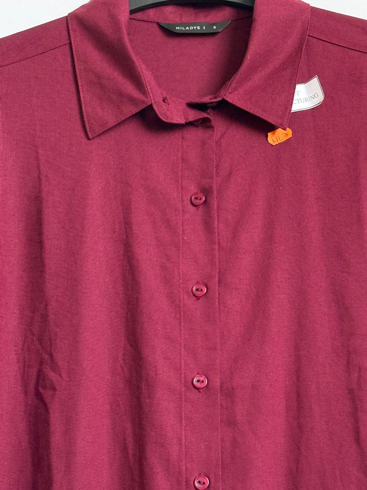 a red shirt is hanging on a hanger