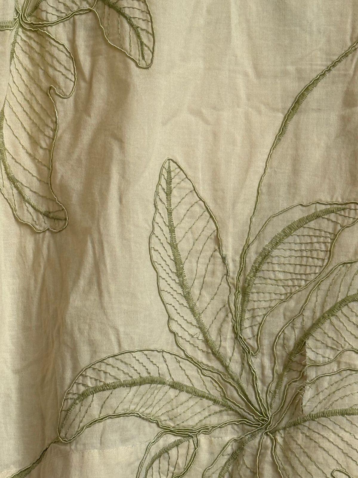 a close up of a white cloth with green leaves on it