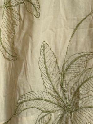 a close up of a white cloth with green leaves on it