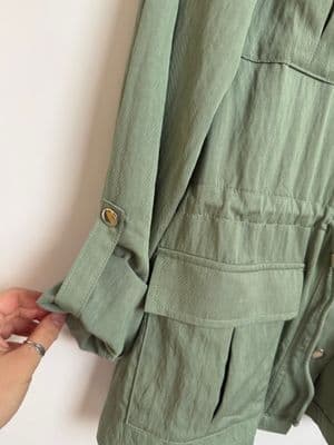 a person putting a button on a green jacket
