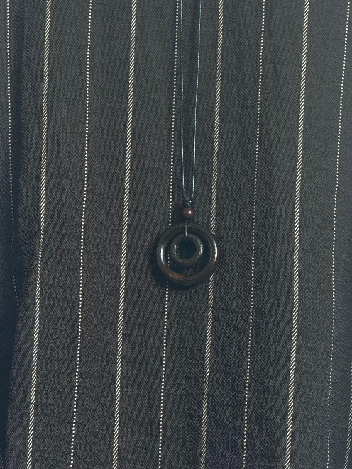 a person wearing a black and white striped shirt and a necklace