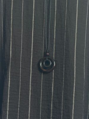 a person wearing a black and white striped shirt and a necklace