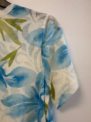 a blue and green flowered shirt hanging on a wall