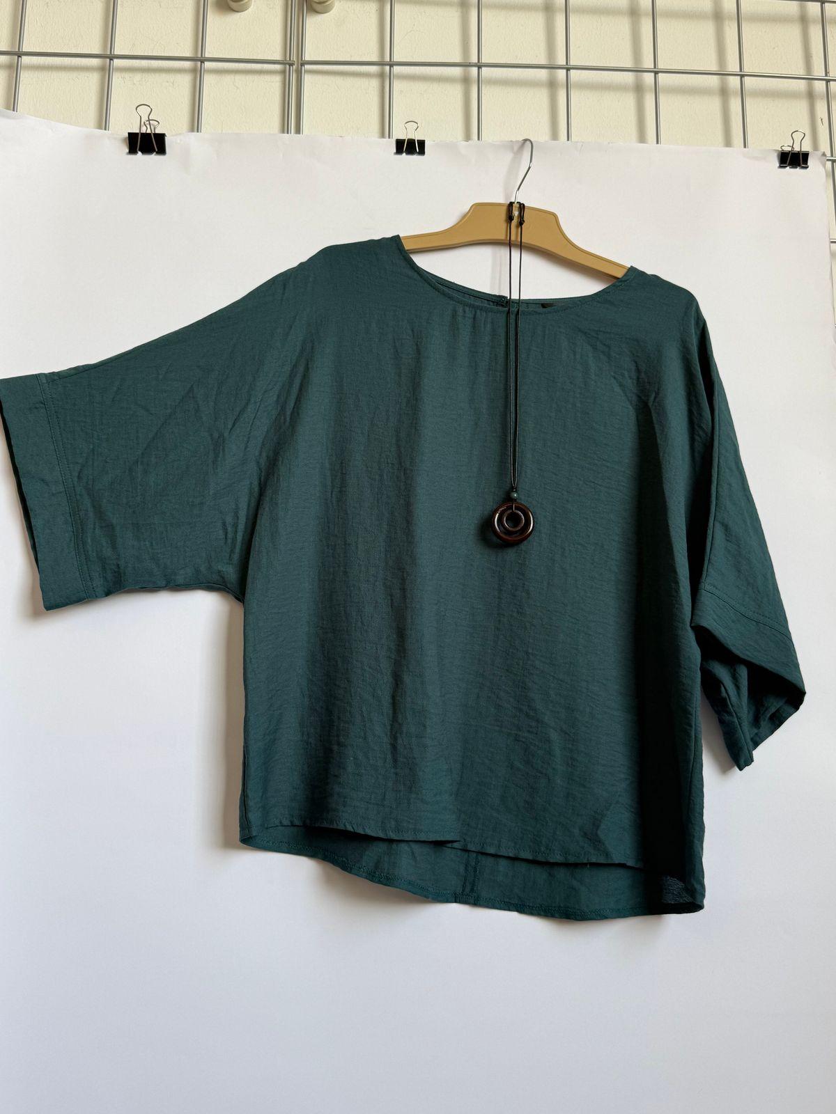 a green top hanging on a white wall