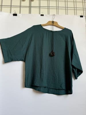a green top hanging on a white wall