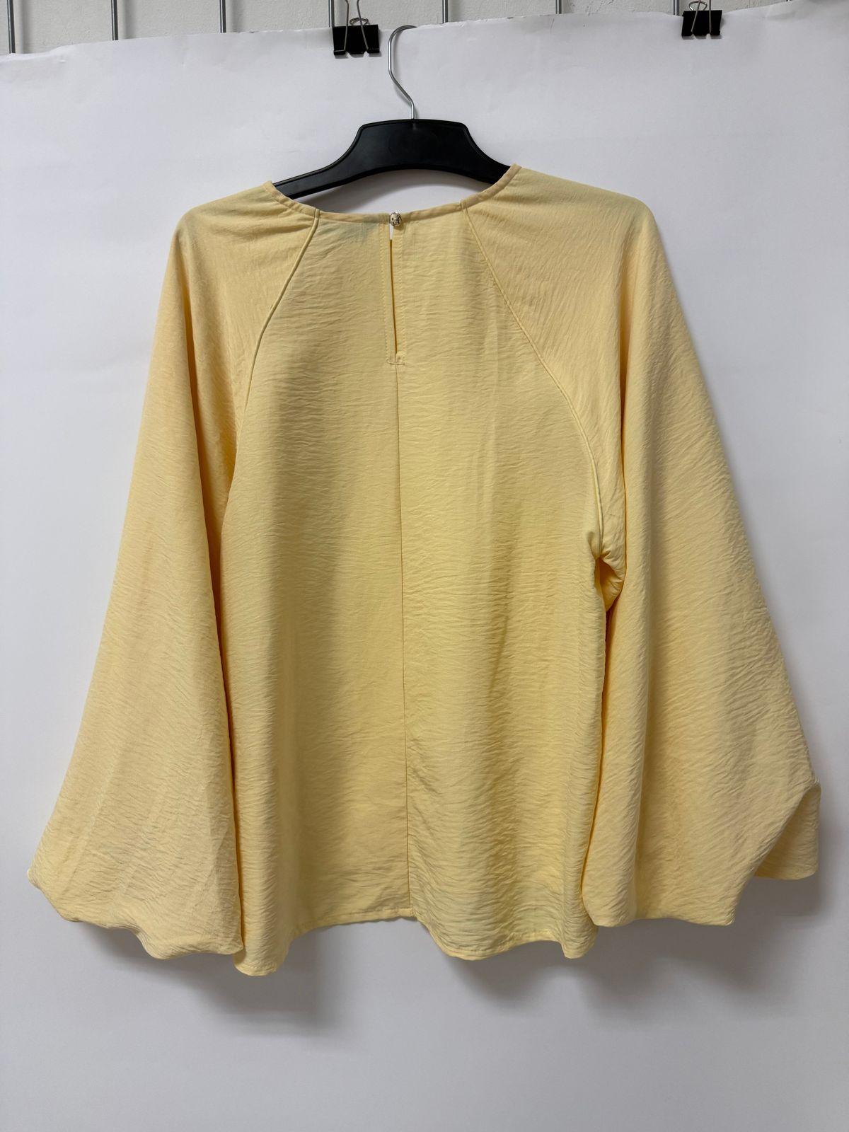 a yellow top hanging on a white wall