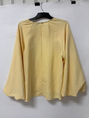 a yellow top hanging on a white wall