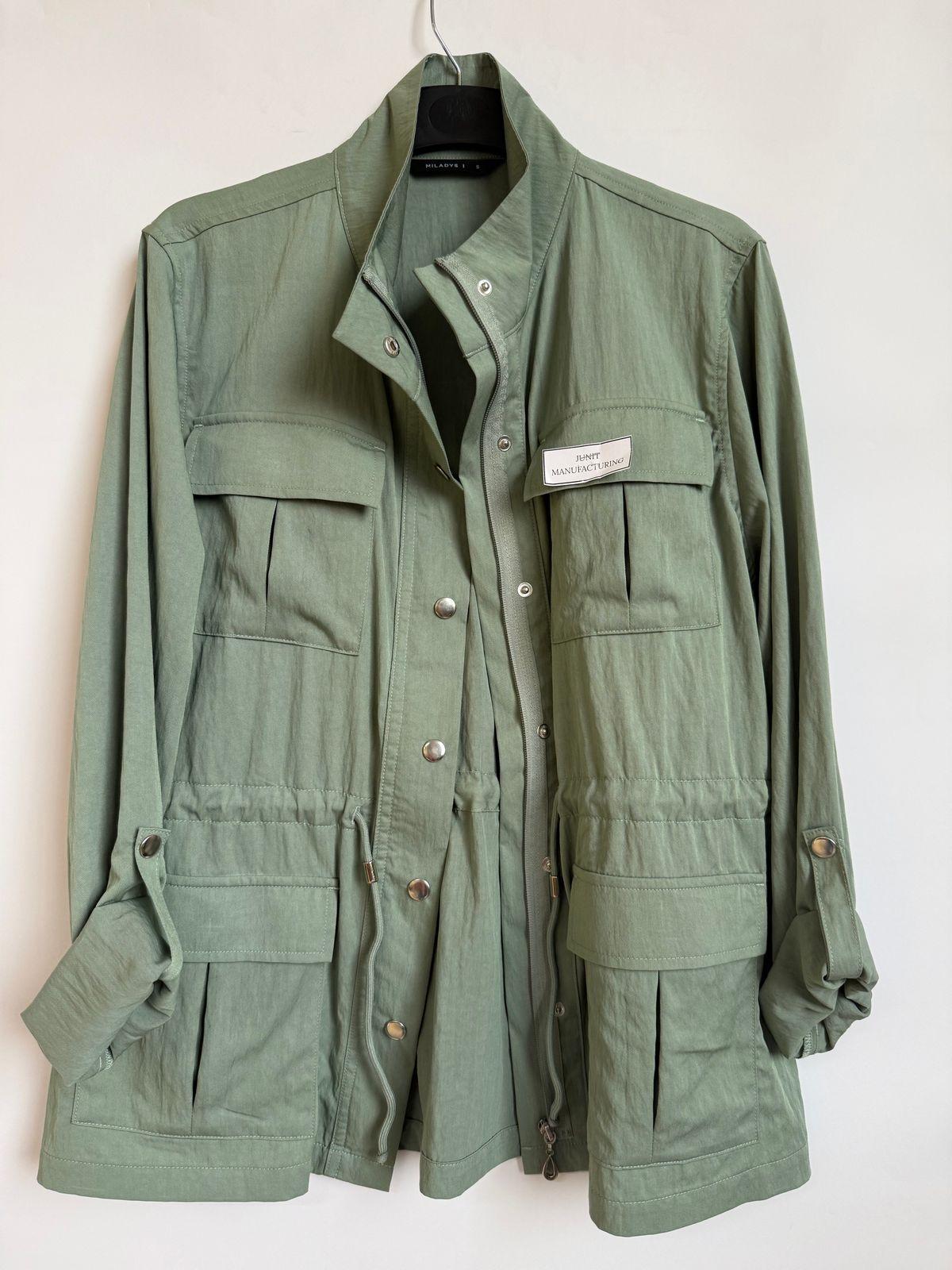 a green jacket hanging on a white wall