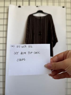a person holding a piece of paper in front of a picture of a shirt
