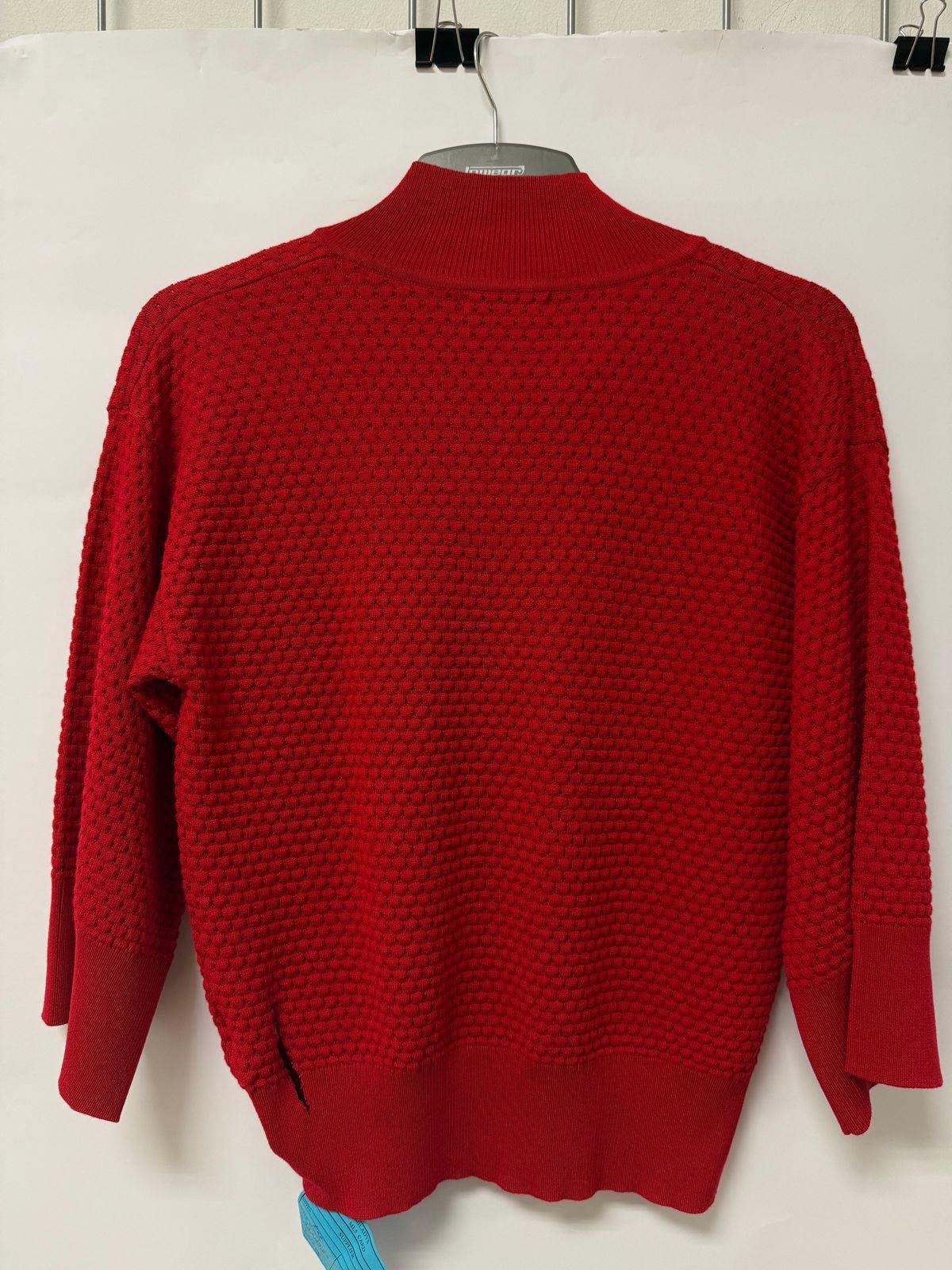 a red sweater hanging on a white wall