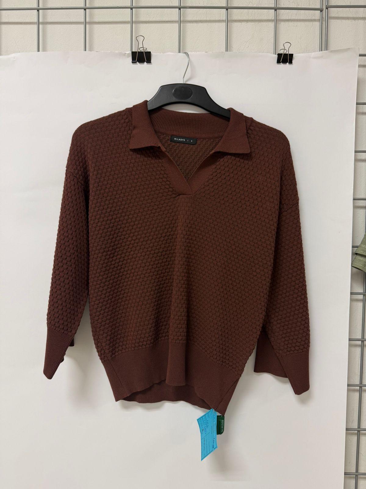 a brown sweater hanging on a white wall