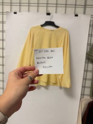 a person holding a piece of paper with a yellow shirt on it