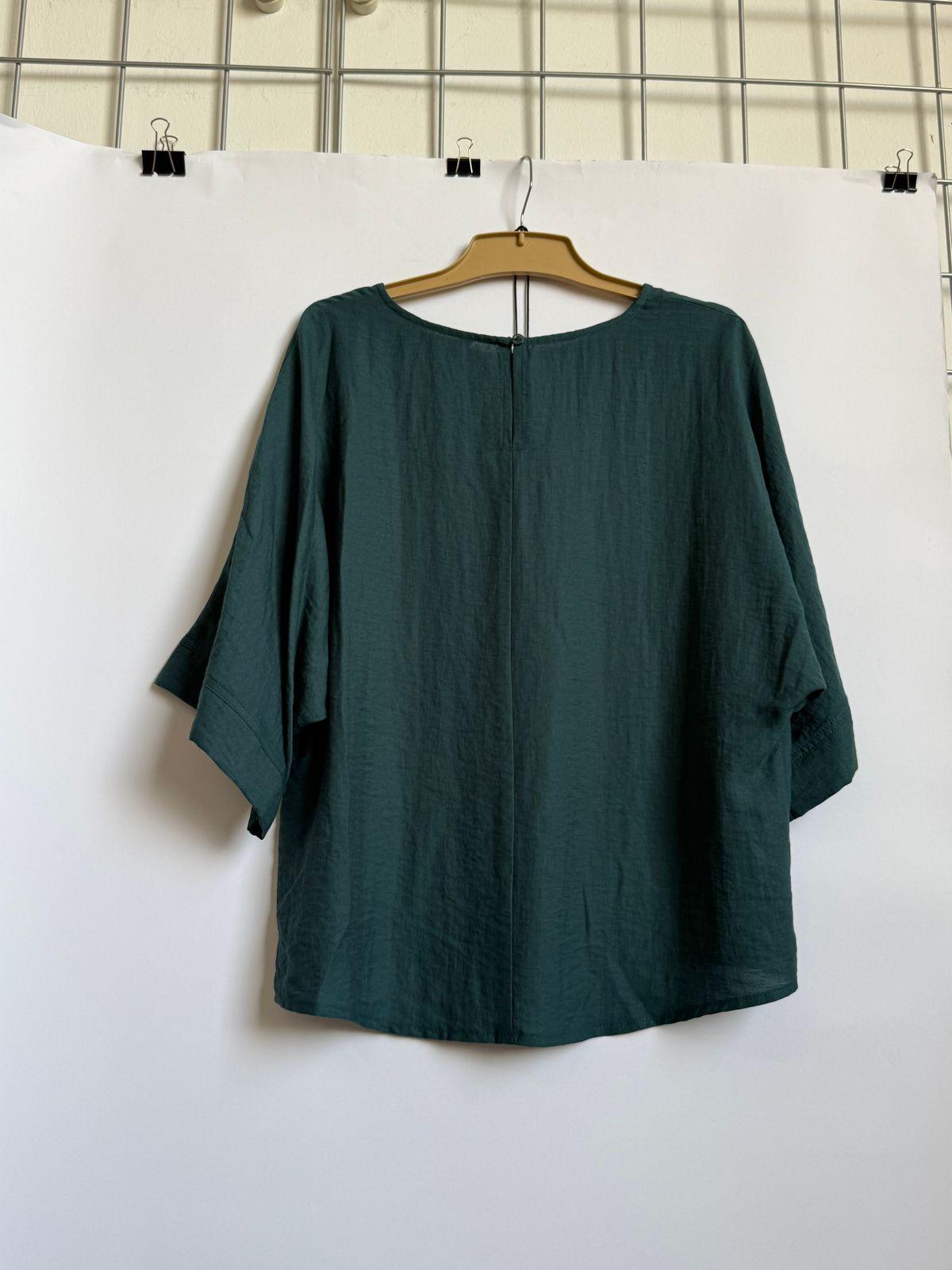 a green top hanging on a white wall