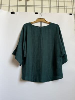 a green top hanging on a white wall
