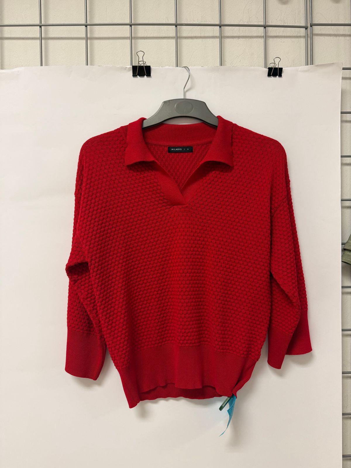 a red sweater hanging on a white wall