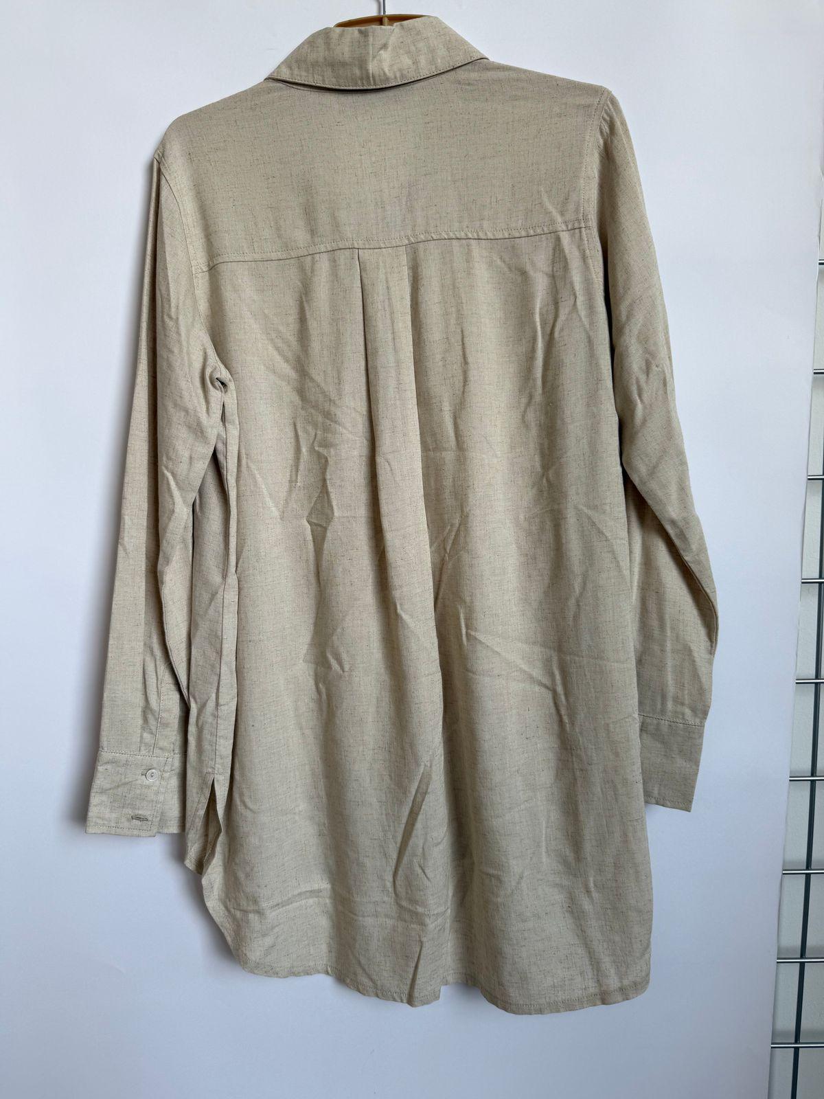 a beige shirt hanging on a white wall