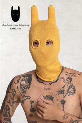 a man with tattoos wearing a yellow bunny mask