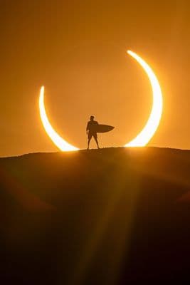 a man holding a surfboard while standing on a hill