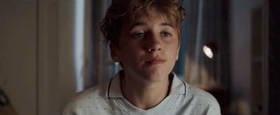 a young man wearing a white shirt looking at the camera