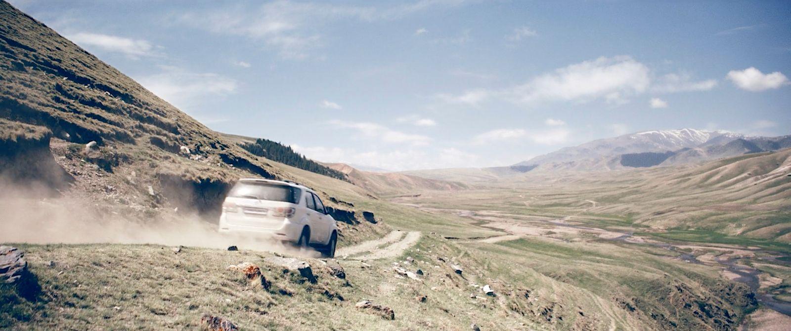 a white car driving down a dirt road
