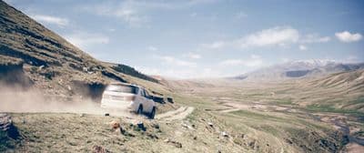 a white car driving down a dirt road
