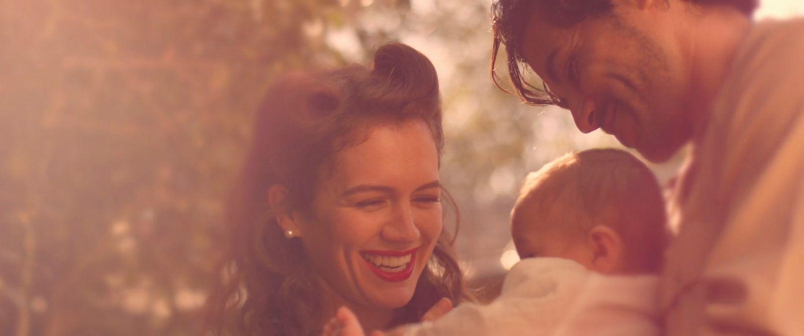 a woman holding a baby and smiling at the camera