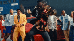 a group of people standing around a red car