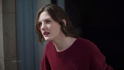 a woman in a red sweater looking off into the distance