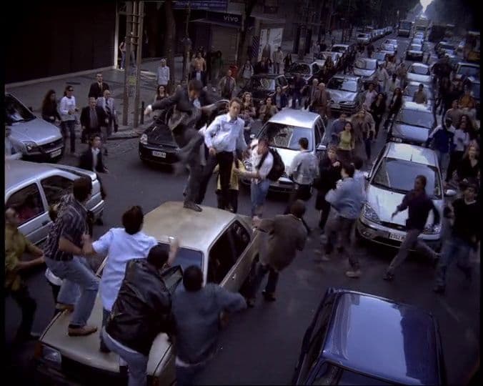 a crowd of people walking down a street next to parked cars