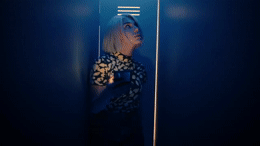 a woman standing in a dark room holding a cell phone