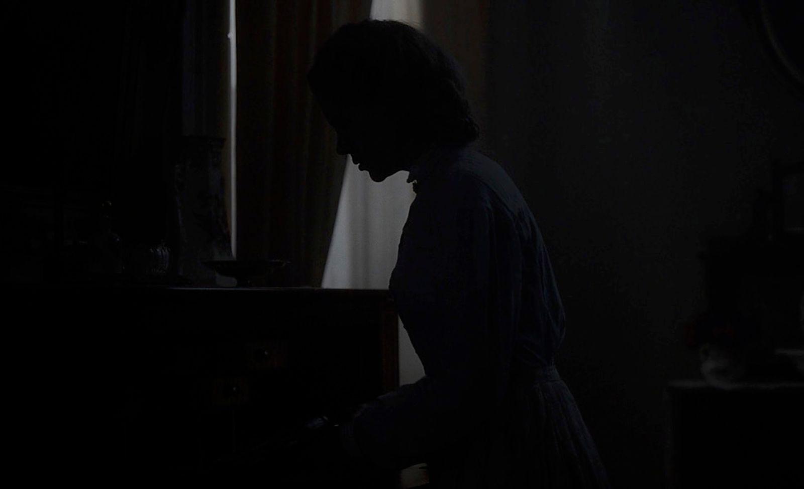 a person standing in a dark room with a piano
